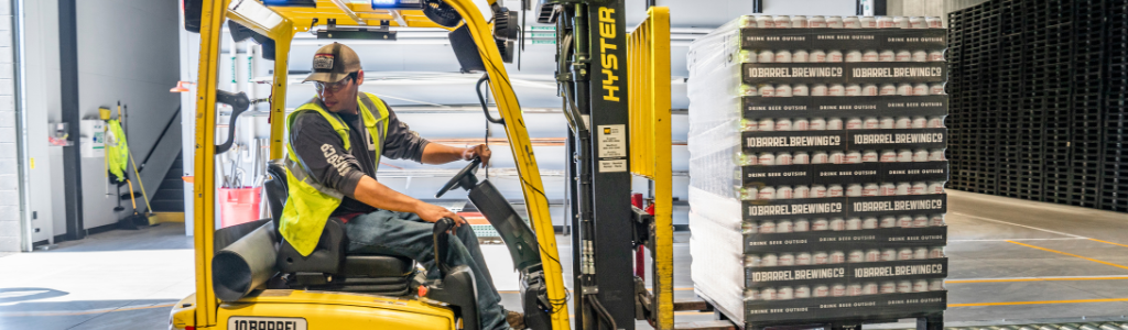 A forklift driver moving a pallet in a warehouse